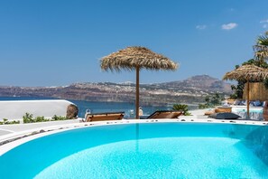 A clear blue pool with lounge chairs and a thatched umbrella, overlooking a scenic coastline. - Summer Lovers Villa (Santorini)