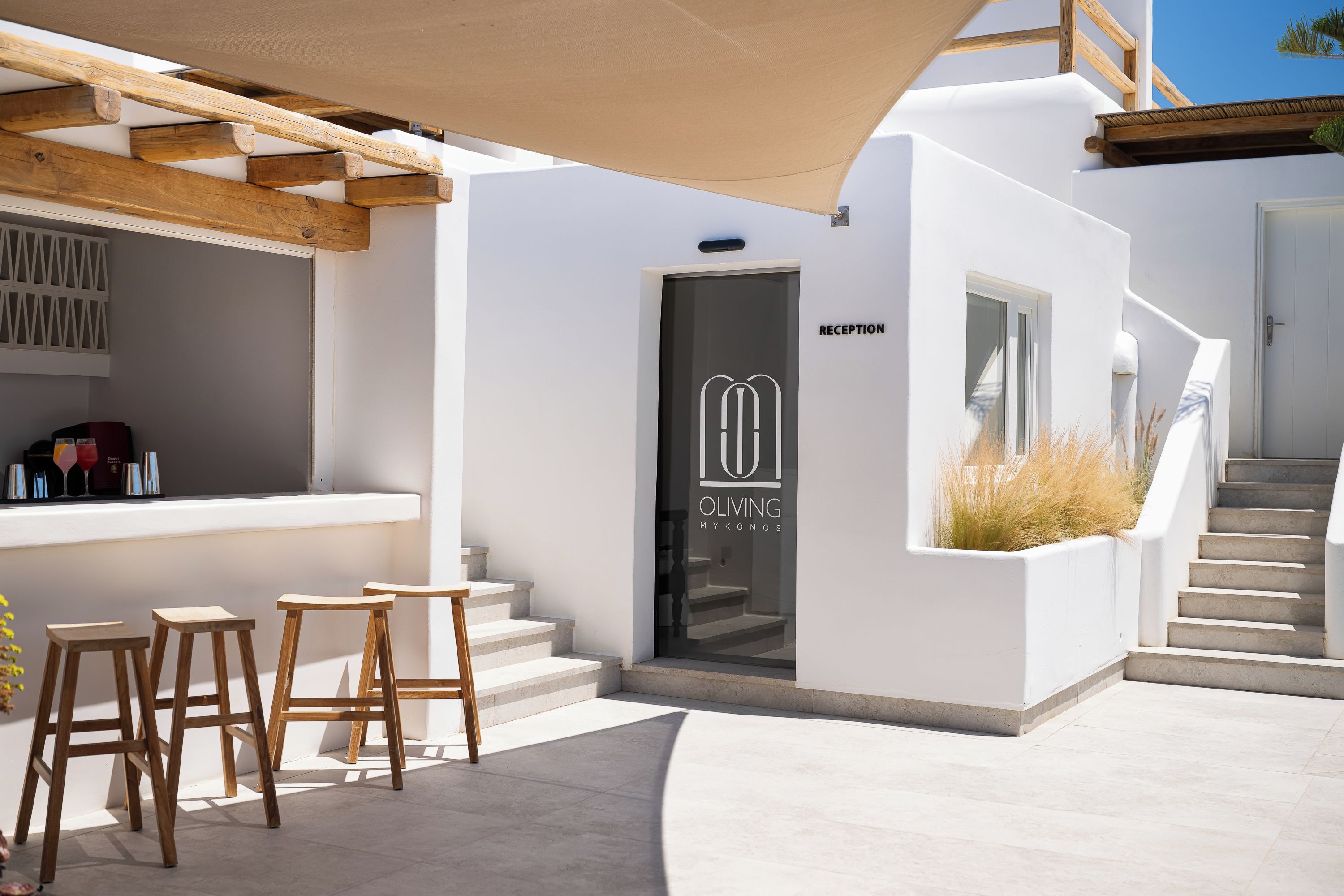 A modern reception area with a wooden pergola, a reception desk, and a staircase leading to an upper level.