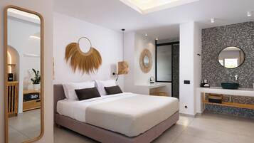 Un dormitorio moderno con una cama grande, mesitas de noche, un espejo y un baño con lavamanos y espejo.