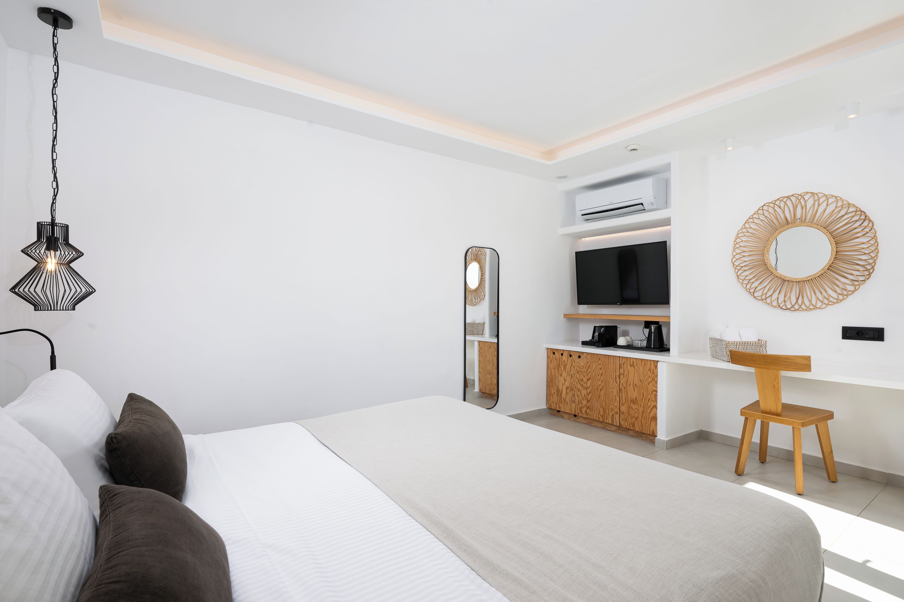 A modern hotel room with a large bed, a desk area, and a TV.