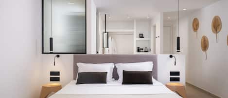 A modern hotel room with a large bed, bedside tables, a wardrobe, and a view of the city.