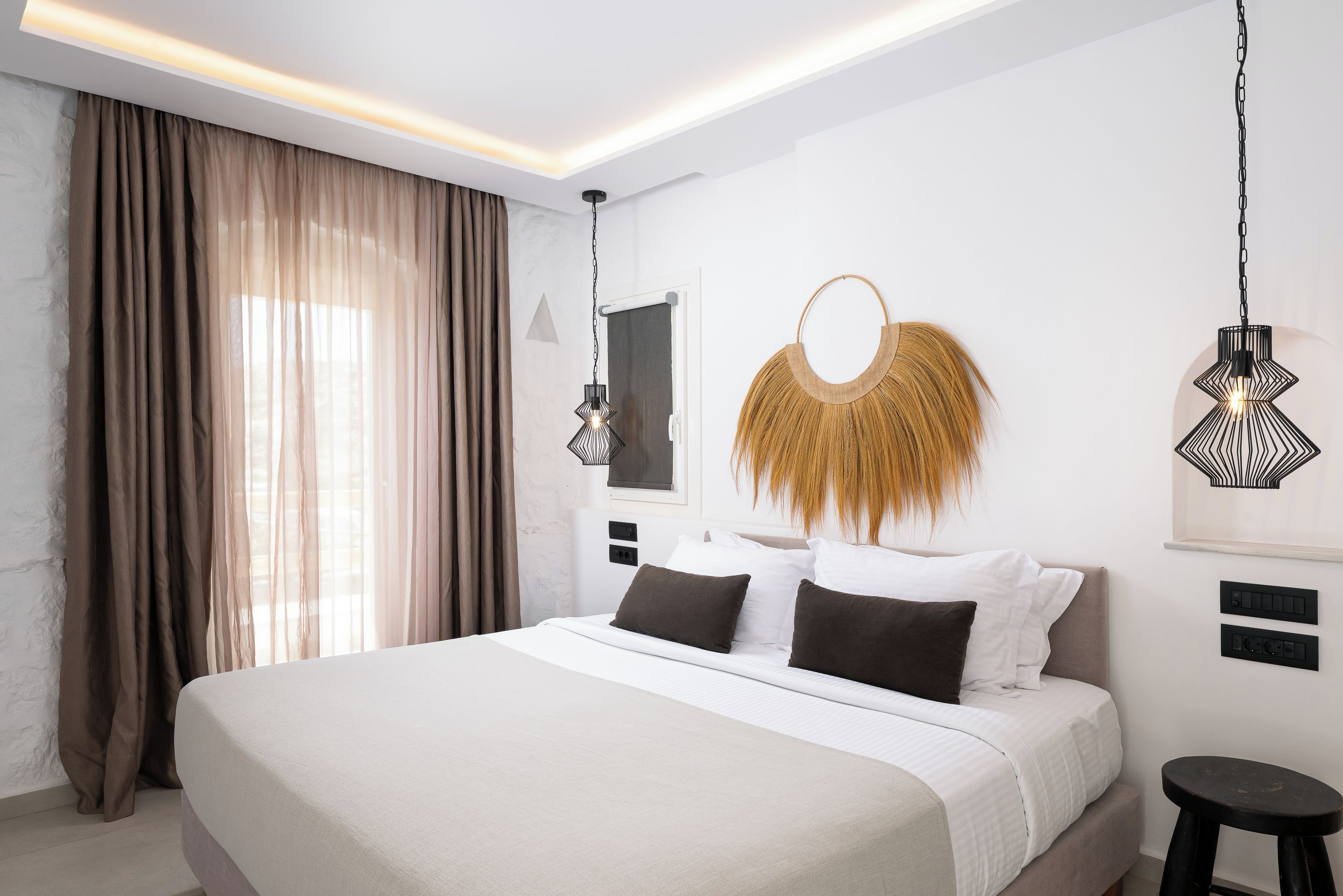Um quarto moderno com uma cama grande, um espelho fixado na parede e iluminação pendente.