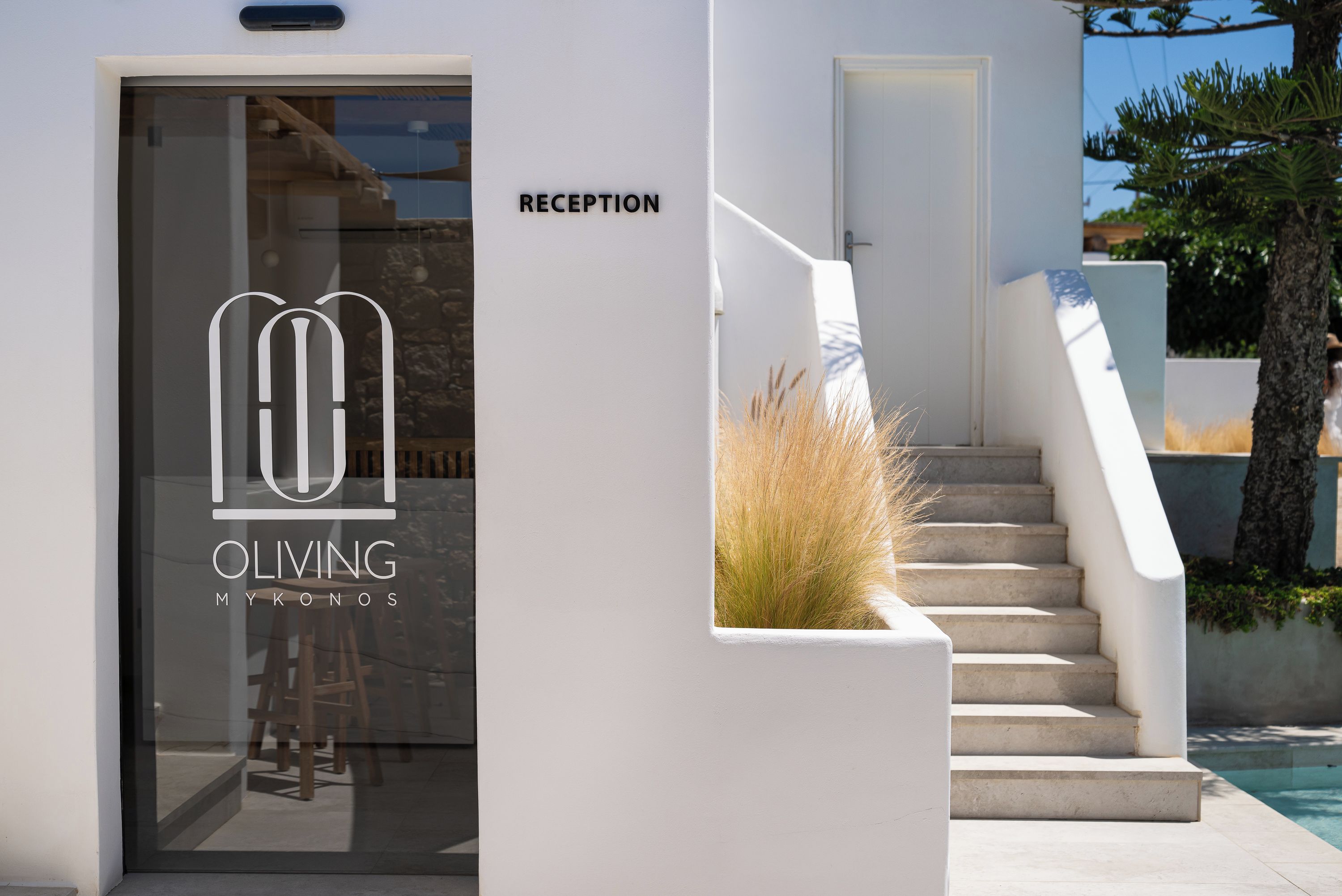 A reception area with a glass door, a staircase, and a poolside view.