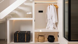 Habitación moderna y luminosa con un armario blanco, una bata colgada y dos cestas.