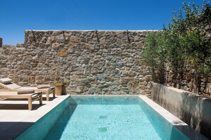 Eine Steinsäule, ein Schwimmbecken und Liegestühle.