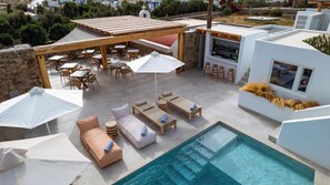 A rooftop pool area with lounge chairs, umbrellas, and a bar.