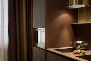 A modern kitchen with a built-in oven, a stovetop, and a pot on the counter.