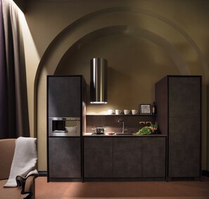 A modern kitchen with a built-in oven, a stainless steel range hood, and a sink.