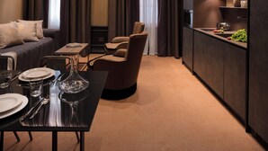 A modern interior with a dining area, a sofa, a chair, and a kitchen with a built-in oven. - Aqua Apartments (Venice)