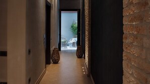 A hallway with a brick wall, a door, and a vase on the floor. - Aqua Apartments (Venice)