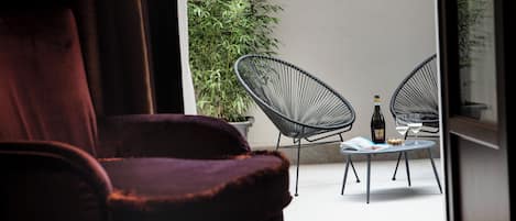 Una habitación con una silla morada, una mesa con dos sillas, una botella y un vaso.
