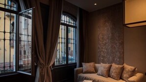 A room with a sofa, a table, and a window with curtains. - Aqua Apartments (Venice)
