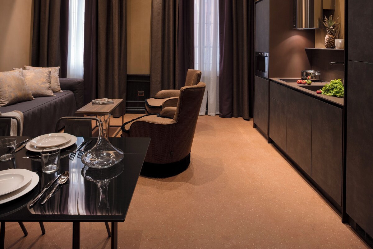 A modern interior with a dining area, a sofa, a chair, and a kitchen with a built-in oven.