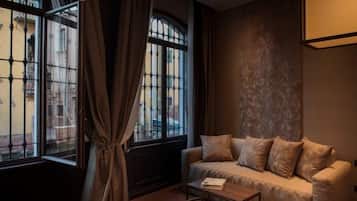 A room with a sofa, a table, and a window with curtains.