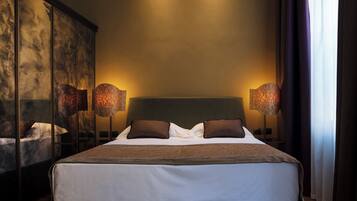 A modern bedroom with a large bed, two bedside lamps, and a large mirror on the left.