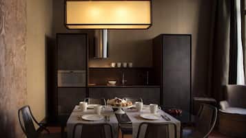 Un moderno comedor con una mesa preparada para cuatro personas, una lámpara colgante grande y un estante empotrado con tazas y un bol pequeño.