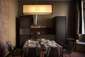 A modern dining area with a table set for four, a large pendant light, and a built-in shelf with cups and a small bowl. - Aqua Apartments (Venice)