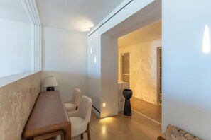 A modern interior with a wooden desk, two chairs, a lamp, and a marble wall. - Numi Boutique Hotel Mykonos (Mykonos)
