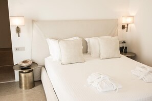 Une chambre d’hôtel avec un grand lit, deux lampes de chevet, une table de chevet avec une lampe, une prise de courant et une petite table ronde avec une télécommande.