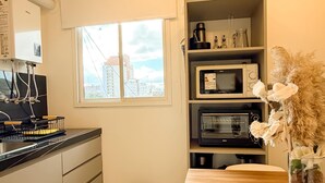 Una cocina moderna con estufa, microondas y fregadero, una mesa de comedor con sillas y vistas a la ciudad a través de una ventana.