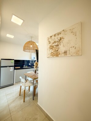 Una cocina moderna con comedor, que incluye un refrigerador, pileta y luces colgantes.