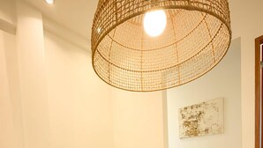 Una sala de estar con un sofá color crema, una mesa de centro blanca y una lámpara de techo trenzada.