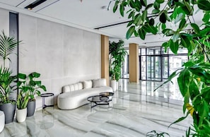 A modern lobby with a white sofa, a coffee table, and potted plants. - Bonita Luxury Resort (Golem)