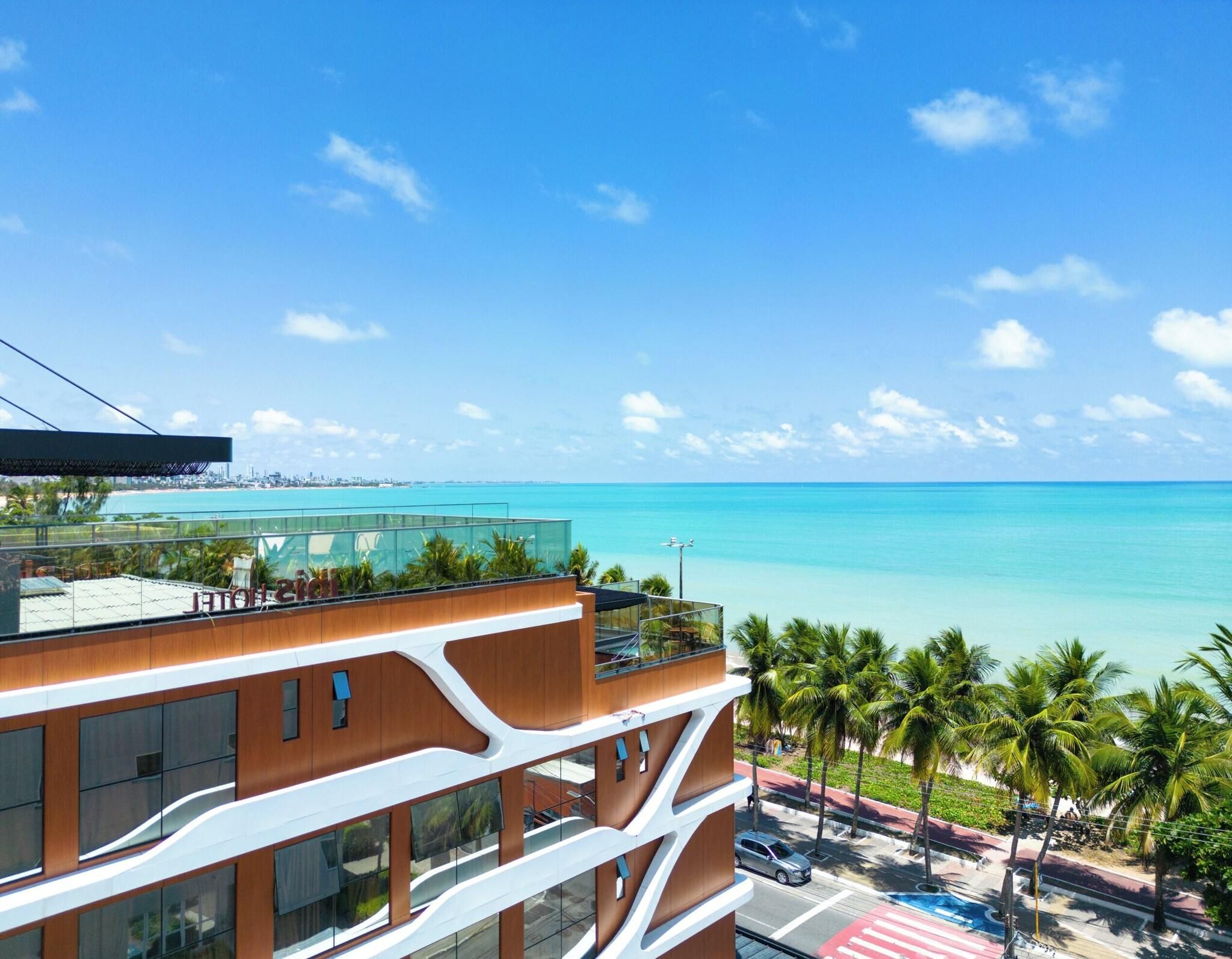 Um hotel moderno com vista para o oceano e palmeiras.