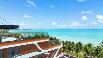 Um hotel moderno com vista para o oceano e palmeiras.