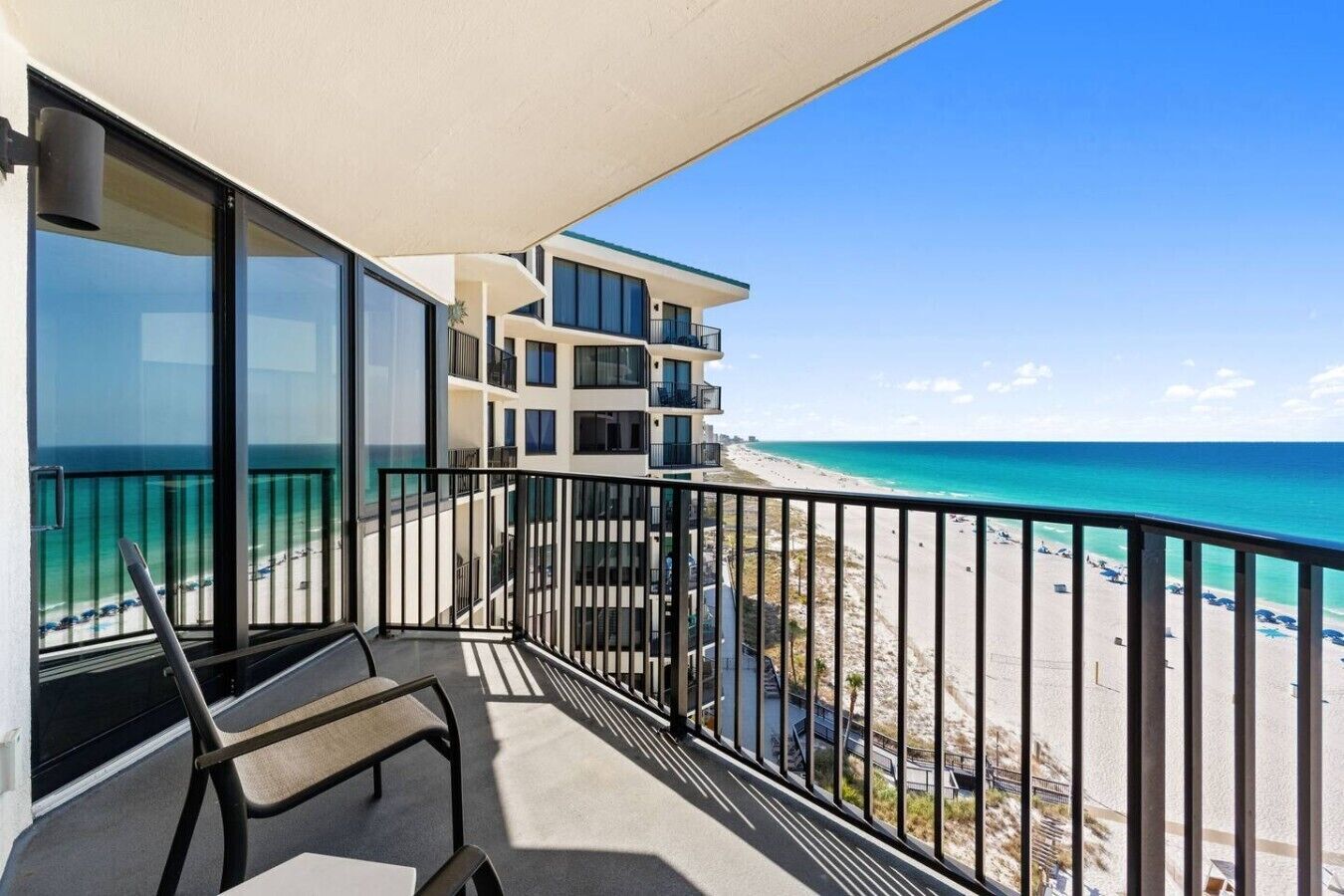 Private beachfront balcony with seating and sweeping views of the sugar-white sand and turquoise Gulf waters.