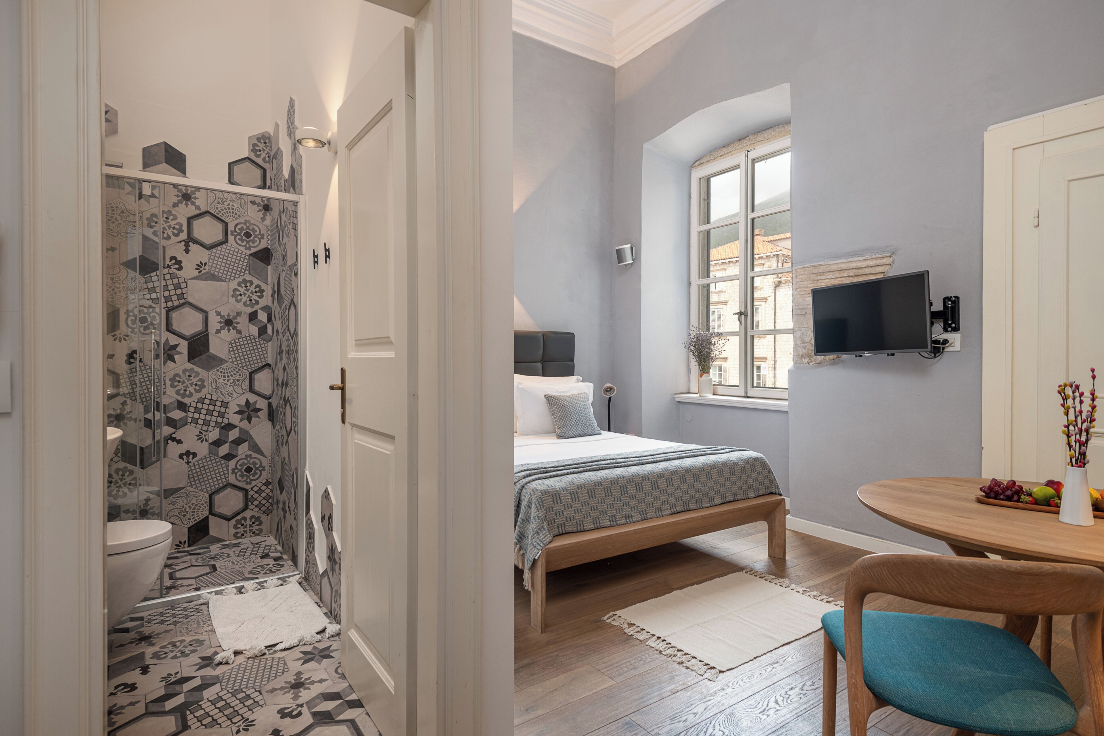 Ein Schlafzimmer mit einem Bett, einem Nachttisch, einem Fernseher und einem Fenster.