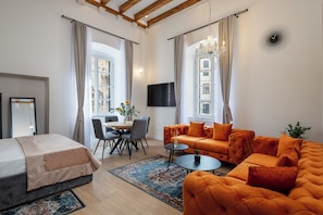 A modern living room with a sofa, a dining table, and a TV. - Helios And Selena (Dubrovnik)