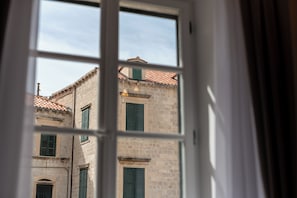 A window with a view of a building with multiple windows and a tiled roof. - Helios And Selena (Dubrovnik)