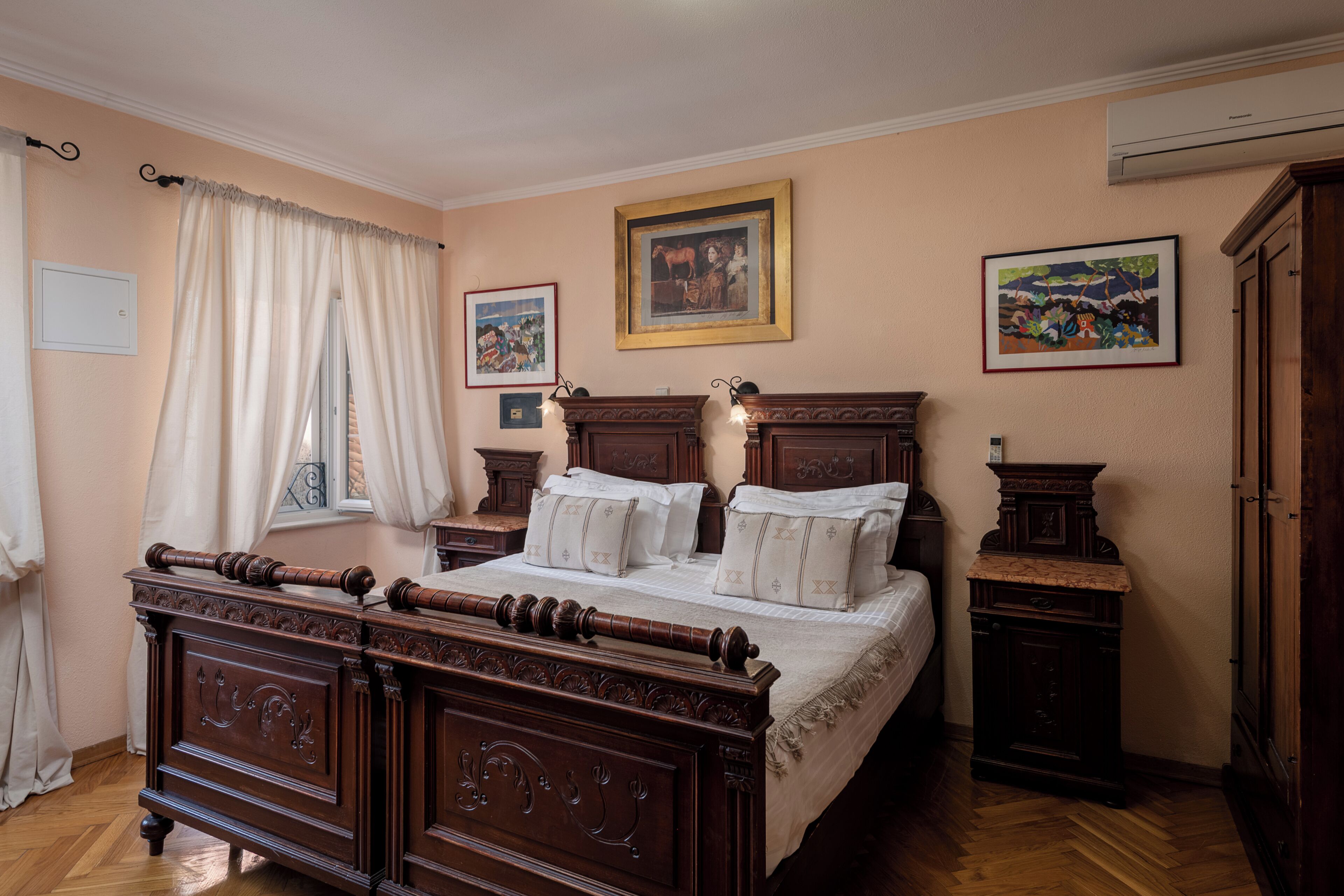 Ein Schlafzimmer mit einem hölzernen Bett, einem Nachttisch, einer Kommode und zwei gerahmten Bildern an der Wand.