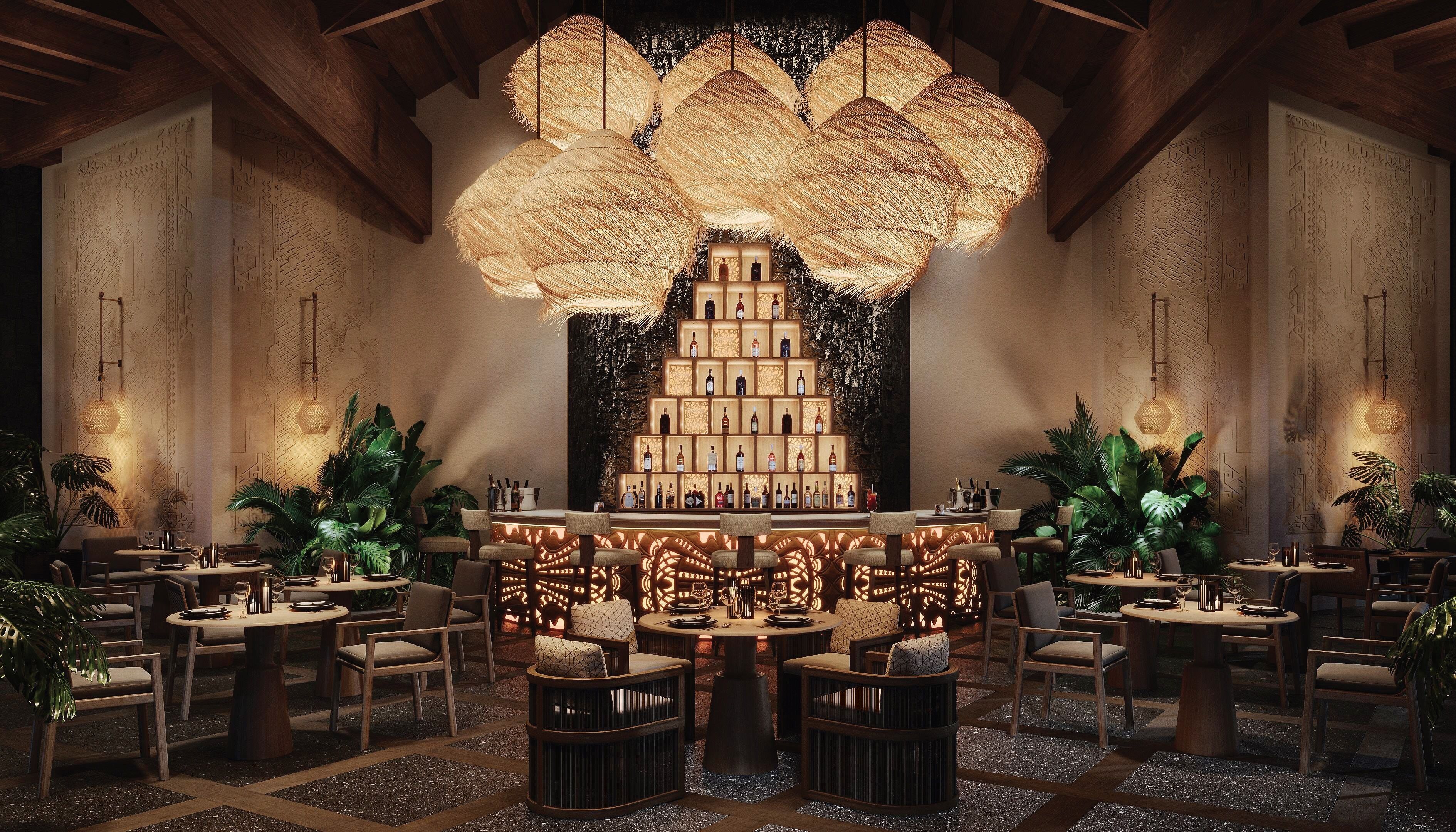 A bar area with a central display of bottles, surrounded by seating and plants.