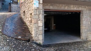 Un edificio de piedra con entrada de garaje, un camino adoquinado y un letrero en la pared.
