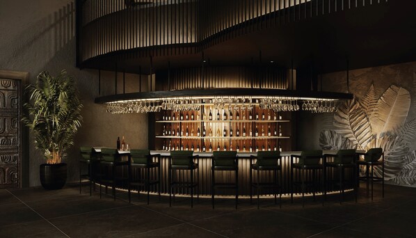 A bar area with a curved counter, multiple shelves of bottles, and a large potted plant. - Lopesan Splash Cove Resort, Spa & Casino (Punta Cana)