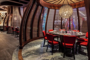 Ein Restaurant mit einem runden Tisch, roten Stühlen und einer großen Pendelleuchte.