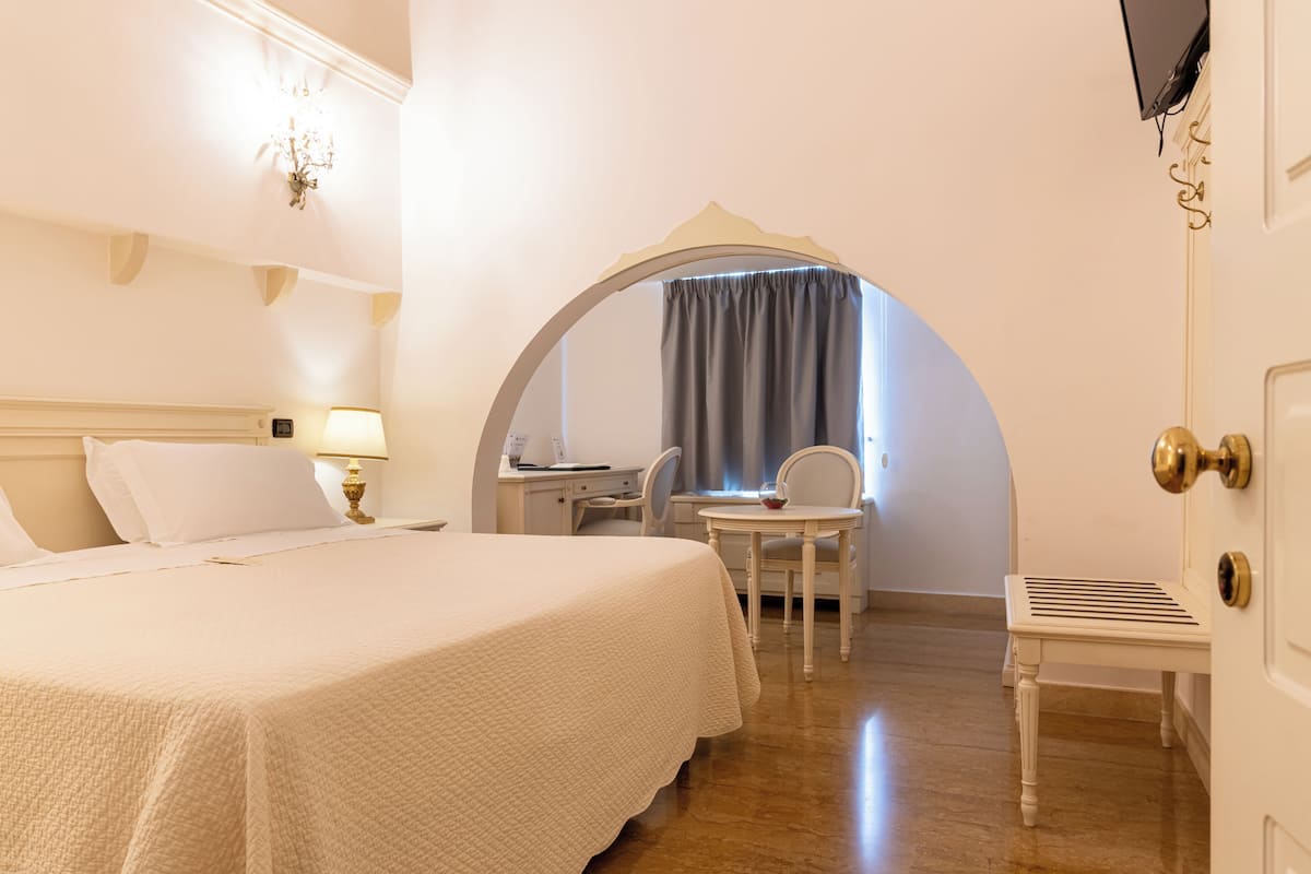 A hotel room with a bed, desk, chair, and a small table.