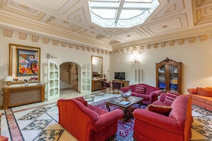 A spacious living room with red sofas, a coffee table, and a chandelier.