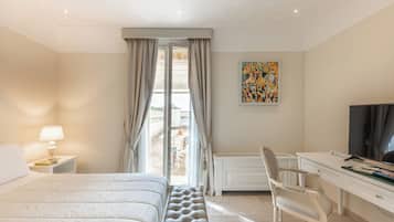 Une chambre d’hôtel équipée d’un lit, d’un bureau, d’une chaise, d’une télévision et d’une fenêtre avec des rideaux.