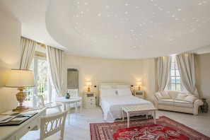 A bedroom with a bed, a desk, a chair, a sofa, and a red patterned rug.