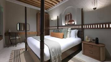 A four-poster bed with a wooden headboard, a bedside table, and a nightstand.