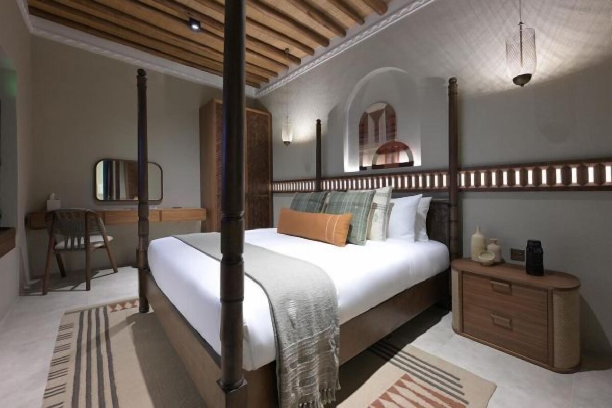 A four-poster bed with a wooden headboard, a bedside table, and a nightstand.