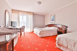 Une chambre d’hôtel avec un lit, un bureau et une chaise, une télévision et un tableau au mur.
