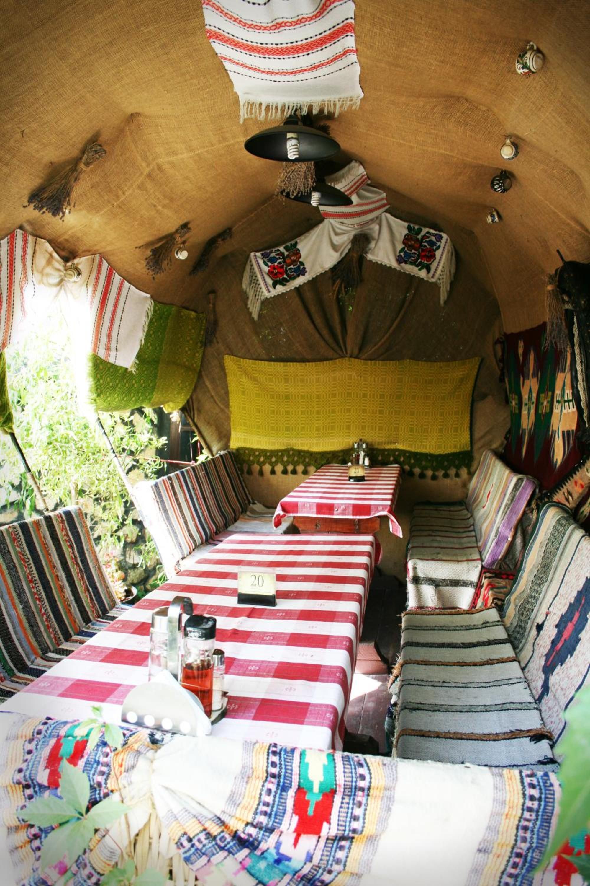 Un intérieur chaleureux avec des tables et des bancs à rayures, une lampe suspendue et une fenêtre donnant sur un beau paysage.