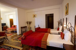 Habitación de hotel con dos camas, un sofá, un televisor y una puerta.