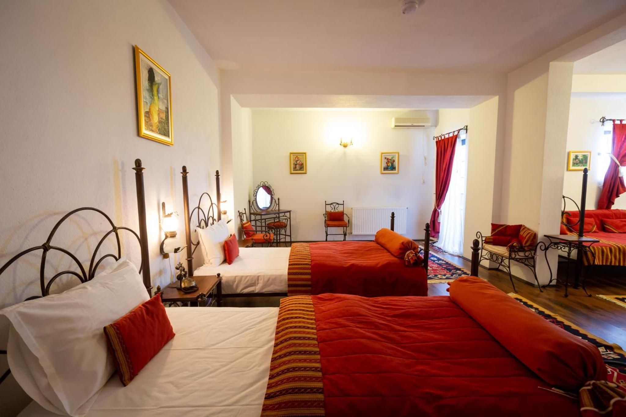 Habitación de hotel con dos camas, una zona de estar con una mesa y sillas, y vista a la calle.