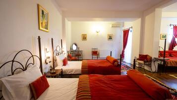 Habitación de hotel con dos camas, una zona de estar con una mesa y sillas, y vista a la calle.