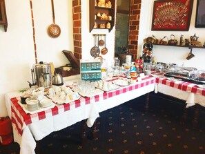 A buffet setup with a variety of food items and utensils on a table covered with a red and white checkered tablecloth. - Complex Turistic Moara Dragaicilor (Mărăcineni)